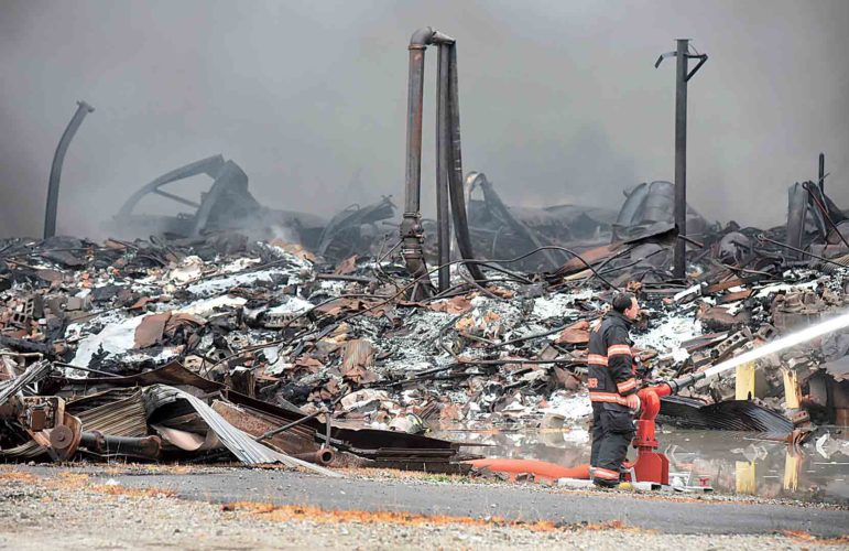 Smoke rises Tuesday from the smoldering remains of the IEI Plastics fire at a warehouse on Camden Avenue.